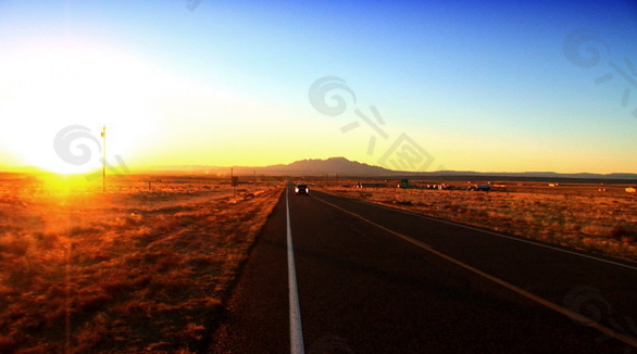 夕阳下公路上行驶的车